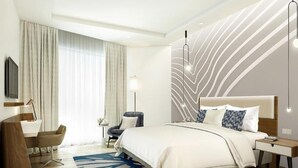 Une chambre d’hôtel moderne, dotée d’un grand lit, d’un bureau et d’une chaise.