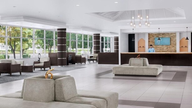A spacious lobby with a reception desk, seating area, and large windows offering a view of the outdoors. - Standard Room In Media City (Dubai)