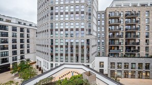 A modern high-rise building with multiple balconies and a central courtyard with greenery.