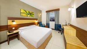 A hotel room with a large bed, a desk, a chair, a TV, and a window with curtains. - Double Room Near Abu Shagara Park by E R (Sharjah)