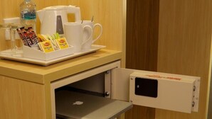 A hotel room with a minibar, a coffee machine, and a tray with tea and snacks. - Double Room Near Abu Shagara Park by E R (Sharjah)