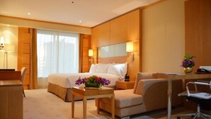 A hotel room with a bed, a desk, a chair, a lamp, and a vase with flowers. - Deluxe Room Near Financial Centre (دبي)