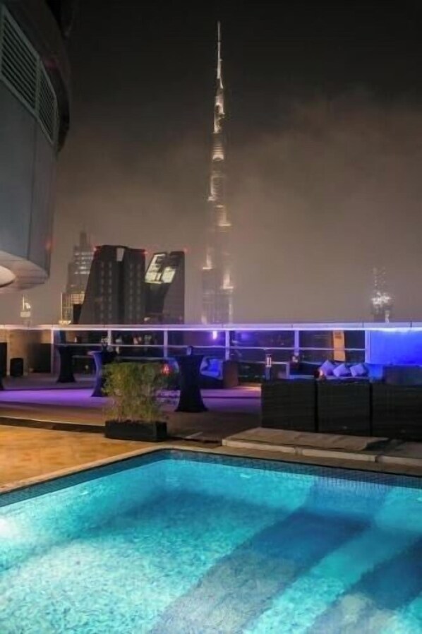 A pool area with a view of a tall building in the background.