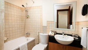 A bathroom with a bathtub, toilet, sink, and a mirror. - Deluxe Room Near Financial Centre (دبي)