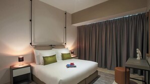 Une chambre d’hôtel moderne avec un grand lit, des tables de chevet, un bureau et une fenêtre avec des rideaux.