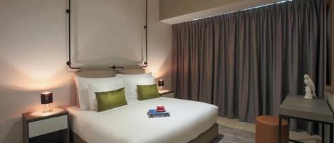 A modern hotel room with a large bed, bedside tables, a desk, and a window with curtains.
