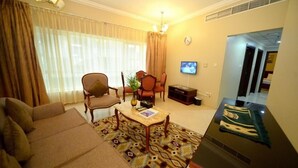 Ein Wohnzimmer mit einer Couch, Sesseln, einem Couchtisch und einem Fernseher.