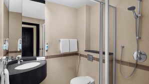 A modern bathroom with a curved sink, a toilet, and a glass-enclosed shower area.