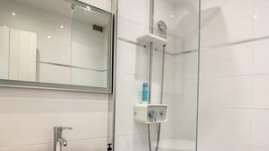 A modern bathroom with a glass-enclosed shower, a white sink, and a wooden vanity. - JUST A LITTLE BIT  (Saint-François)