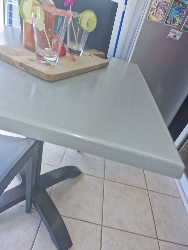 A kitchen counter with a table, two glasses of a beverage with lime slices and a pink garnish, and a refrigerator in the background. - JUST A LITTLE BIT (Saint-François)