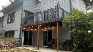 Ein zweistöckiges Haus mit Balkon, Lichterkette und Terrassenbereich.