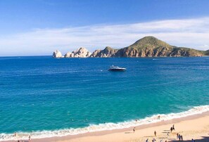 A beach with clear blue water, a boat, and rocky cliffs in the background. - Luxury Modern Villa- 5min walk to marina/downtown. Gated Community. Game room. (Cabo San Lucas)