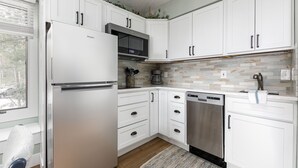 A modern kitchen with white cabinets, a stainless steel refrigerator, a dishwasher, and a microwave. - The Shores Lake View Condo Unit 5689 (Williamsburg)