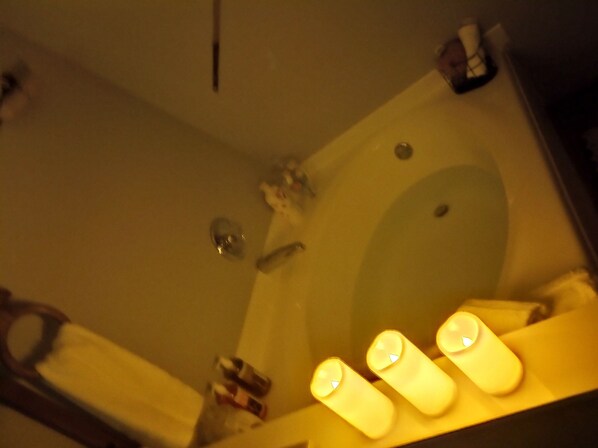 A bathroom with a sink, mirror, and three lit candles.