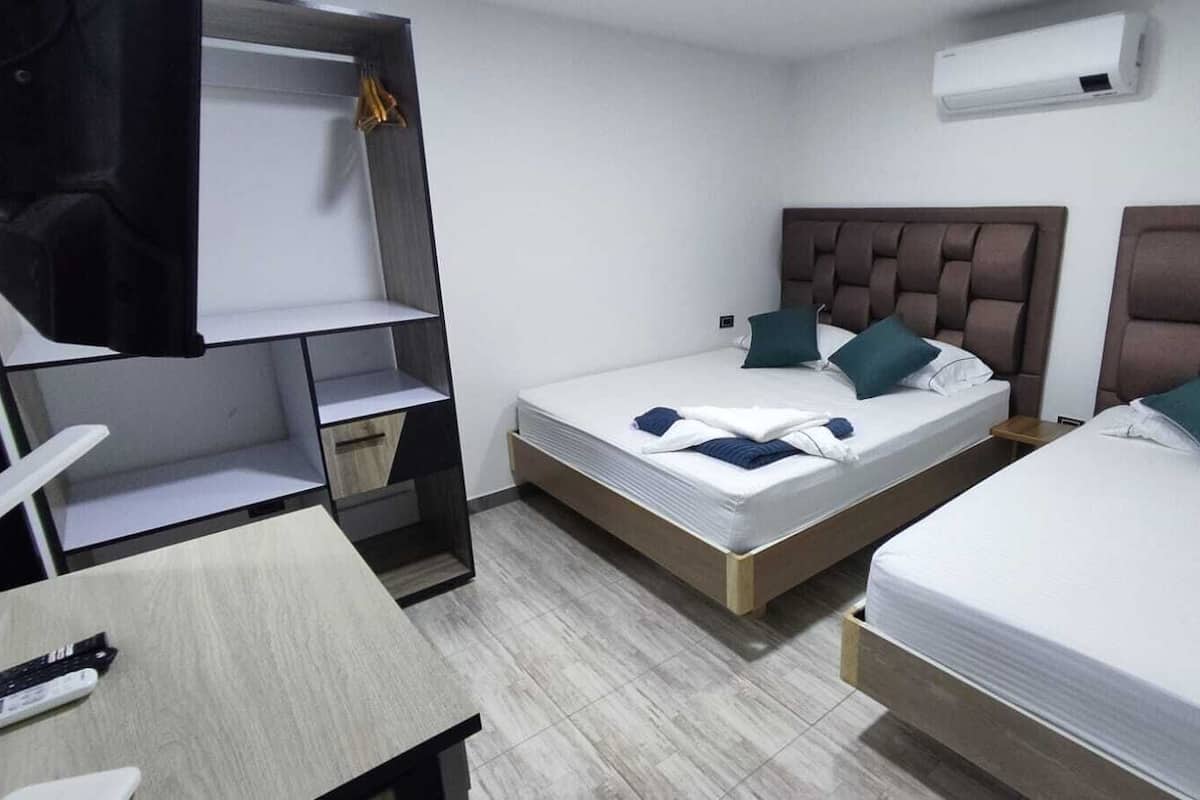 Quarto de hotel com duas camas, uma escrivaninha e um guarda-roupa.