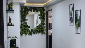 A hallway with a green leafy wall decoration, a mirror, and two ottomans. - Cra. 81 No. 37d - 17 (Medellín)