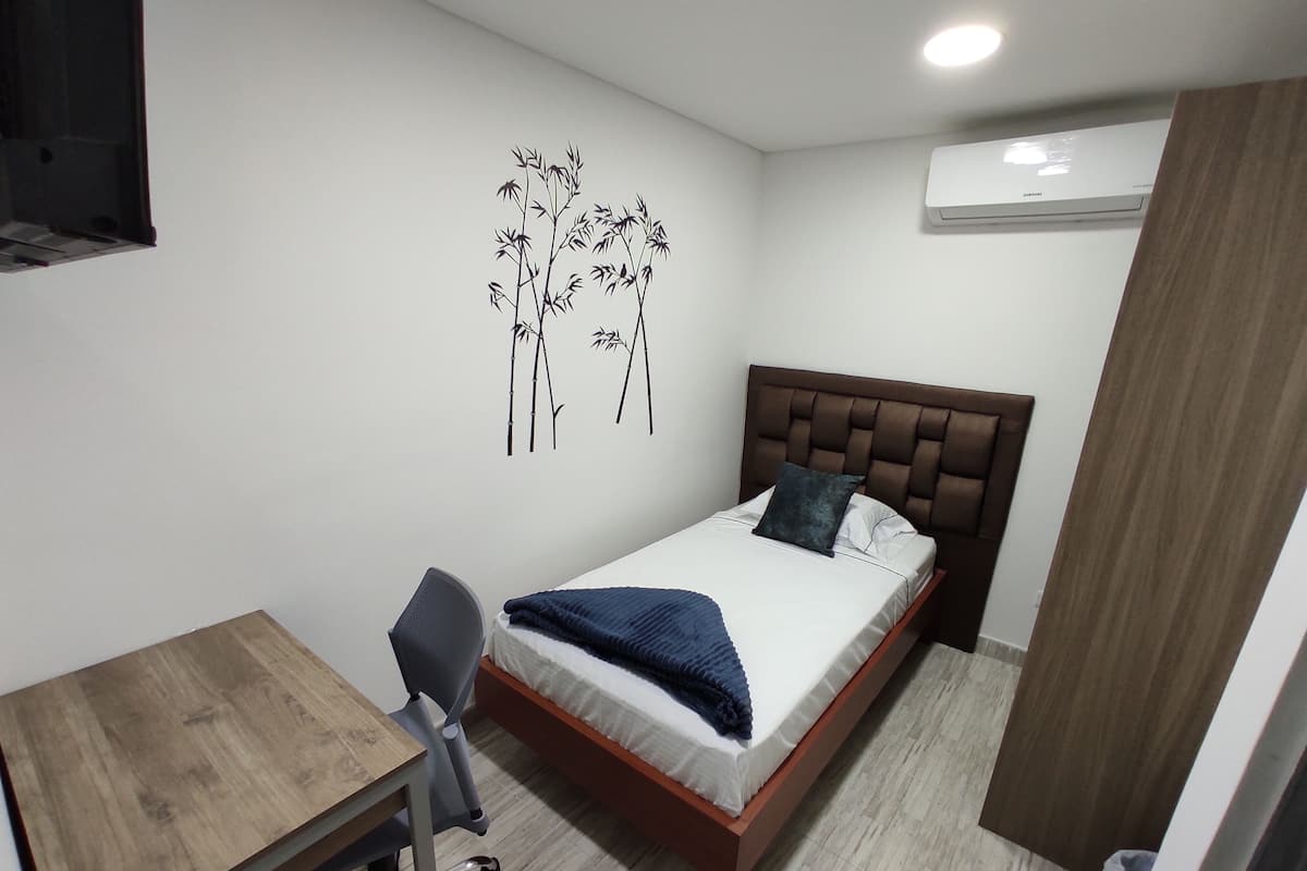 Quarto com cama, escrivaninha e cadeira.