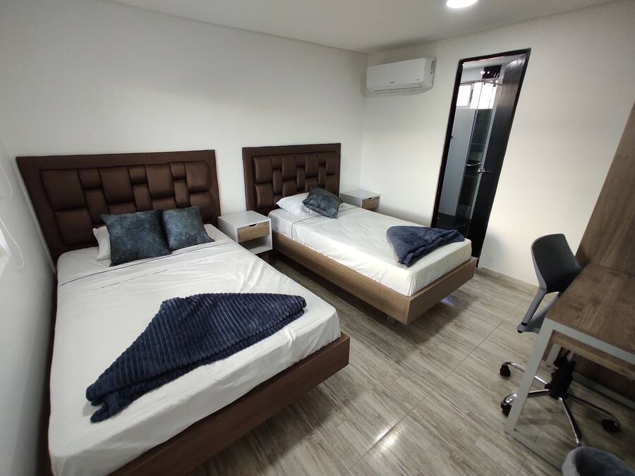 Una habitación de hotel con dos camas, un escritorio, una silla y un equipo de aire acondicionado.