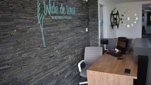 A modern office space with a stone wall, a wooden desk, and a wall clock. - Cra. 81 No. 37d - 17 (Medellín)