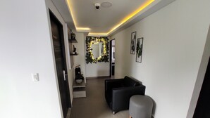 A modern hallway with a black sofa, a grey ottoman, and a decorative plant arrangement. - Cra. 81 No. 37d - 17 (Medellín)