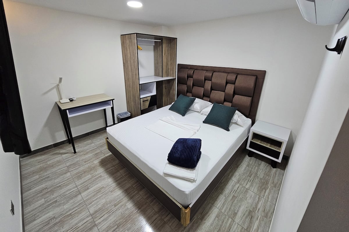 Quarto de hotel moderno com uma cama grande, uma escrivaninha e um guarda-roupa.