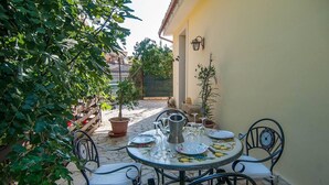 An outdoor patio with a round table set for dining, surrounded by chairs, and potted plants. - Cottage - Sleeps 4 - Parking - Garden (Noto)