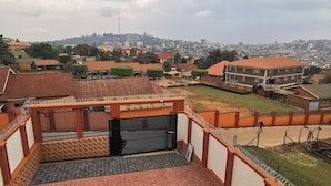 Una terraza en la azotea con piso estampado, una entrada con reja y vista a un paisaje urbano.