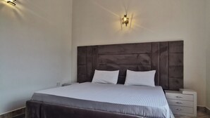 Un dormitorio moderno con una cama grande, un cabecero oscuro y una alfombra mullida.