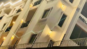 Un edificio de varios pisos con un diseño arquitectónico moderno, con balcones y ventanas iluminadas.