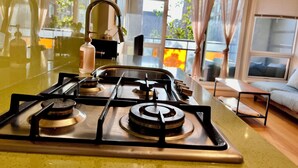 A modern kitchen with a gas stove, a stainless steel sink, and a window overlooking a cityscape. - Modern 1BR w/ Balcony | 10 Mins Walk to BC Place & Rogers Arena (Vancouver)