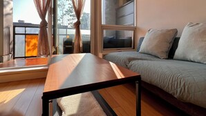 A room with a wooden table, a bed with pillows, a window with curtains, and a clock on the wall. - Modern 1BR w/ Balcony | 10 Mins Walk to BC Place & Rogers Arena (Vancouver)
