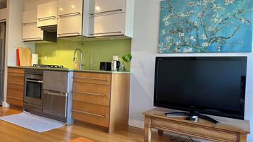 A modern kitchen with white cabinets, a stainless steel oven, and a wooden dining table.