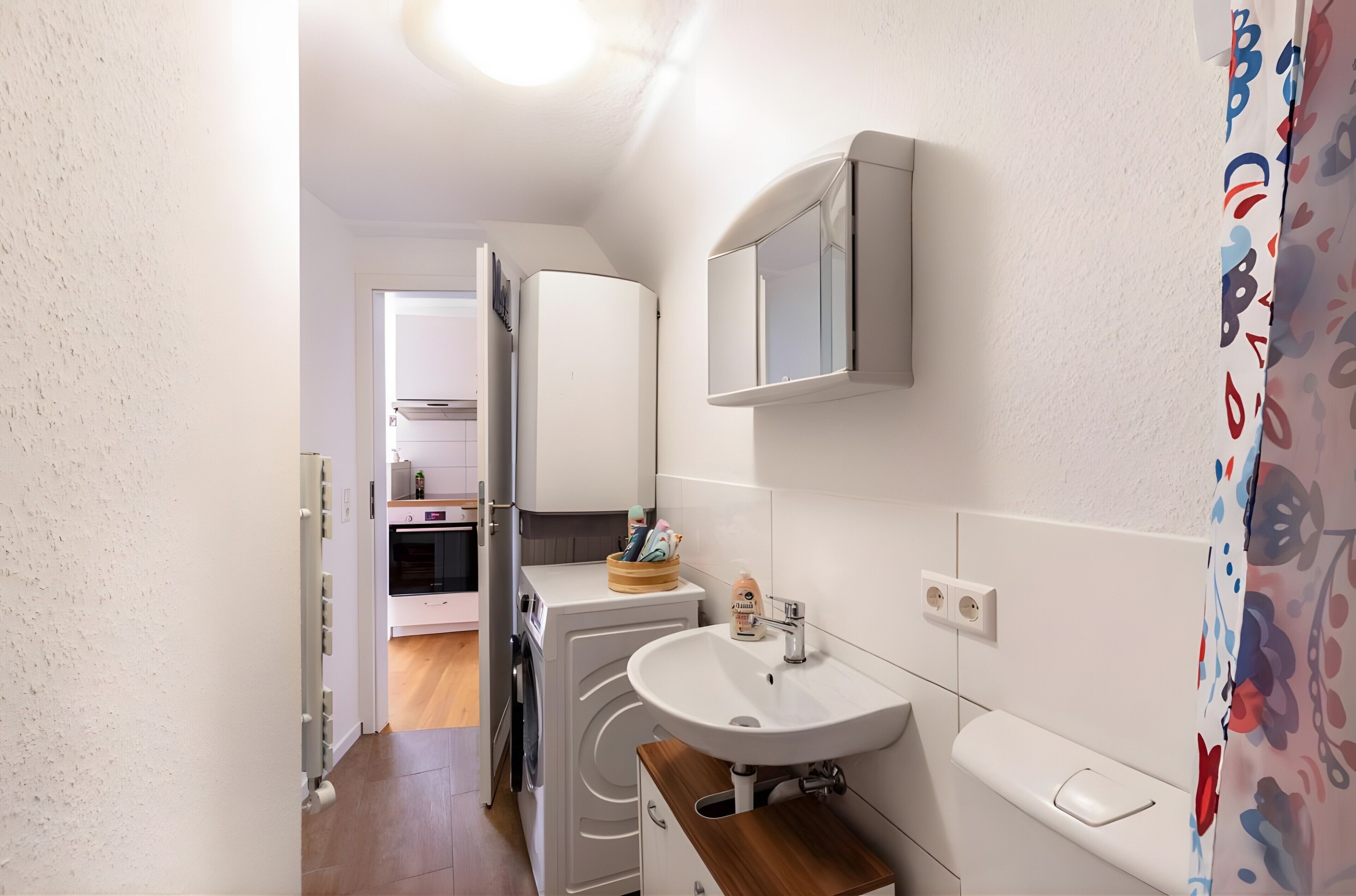 A compact kitchen with a built-in oven, a sink, and a mirror above it.