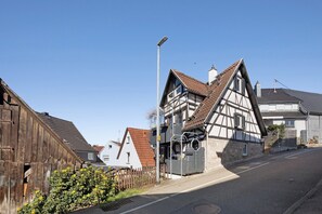 A traditional half-timbered house with a sloped roof, a street lamp, and a clear blue sky.