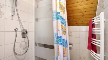 Une douche avec un flexible en métal, un rideau de douche à motifs et un plafond en bois.