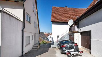 A narrow street with a parked car and a satellite dish on a building.