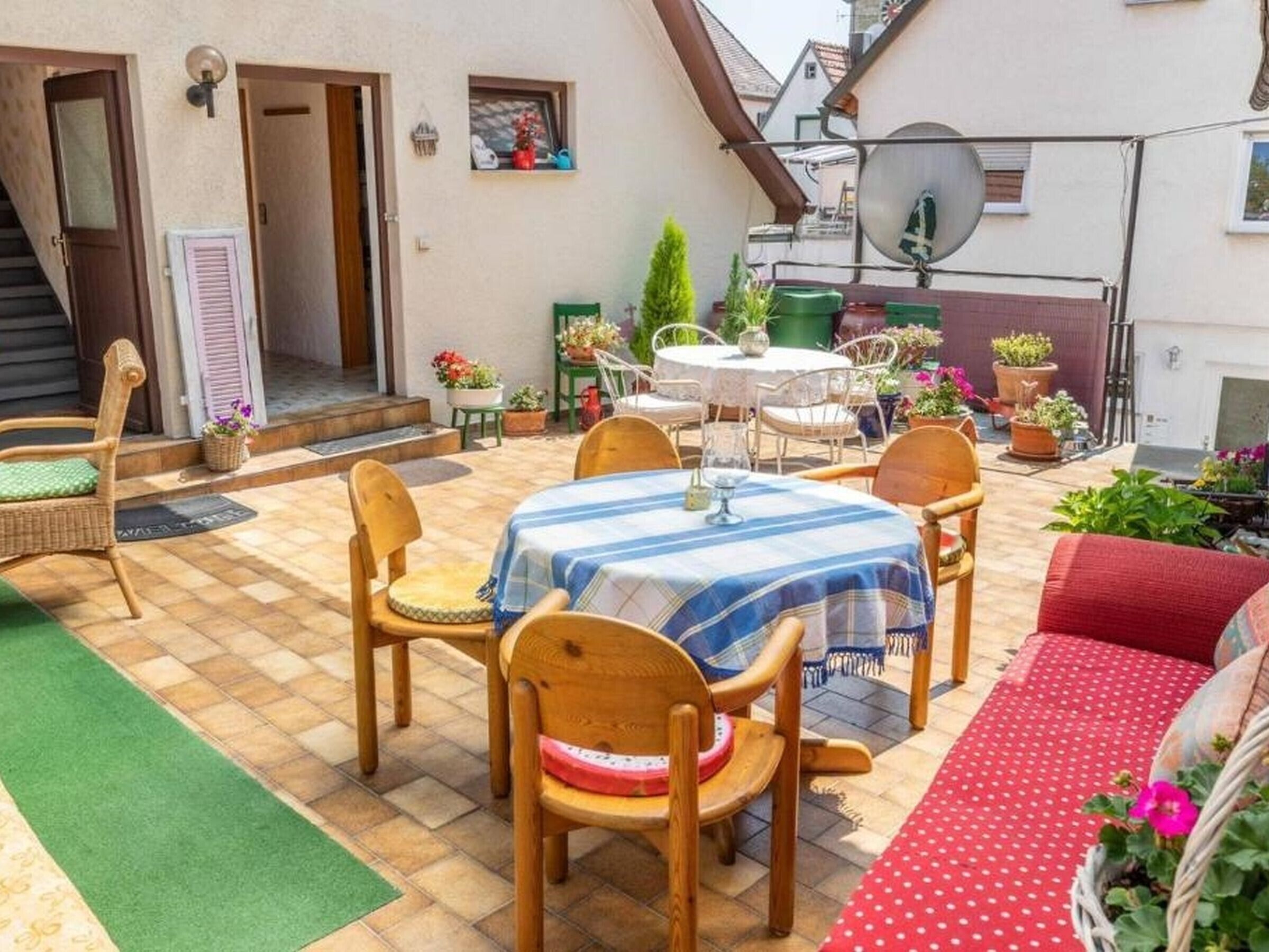 A patio with a table and chairs, surrounded by potted plants and a small garden.