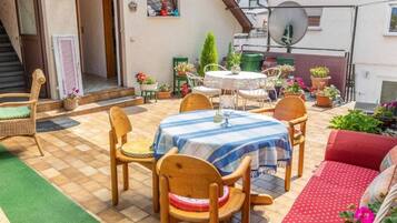 A patio with a table and chairs, surrounded by potted plants and a small garden.