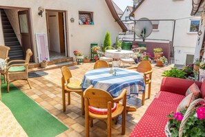 Un espace patio avec une table ronde, des chaises et un canapé rouge.