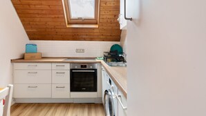 Una cocina compacta con horno integrado, lavadora y ventana sobre el fregadero.