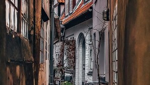 Un estrecho callejón flanqueado por edificios, con arquitectura tradicional, ventanas visibles y tejado de tejas.
