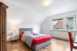 Ein Schlafzimmer mit einem Bett, einem Nachttisch, einem Fenster und einer Heizung.