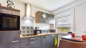 Una cocina moderna con horno empotrado, cafetera y ventana con vistas a un jardín.