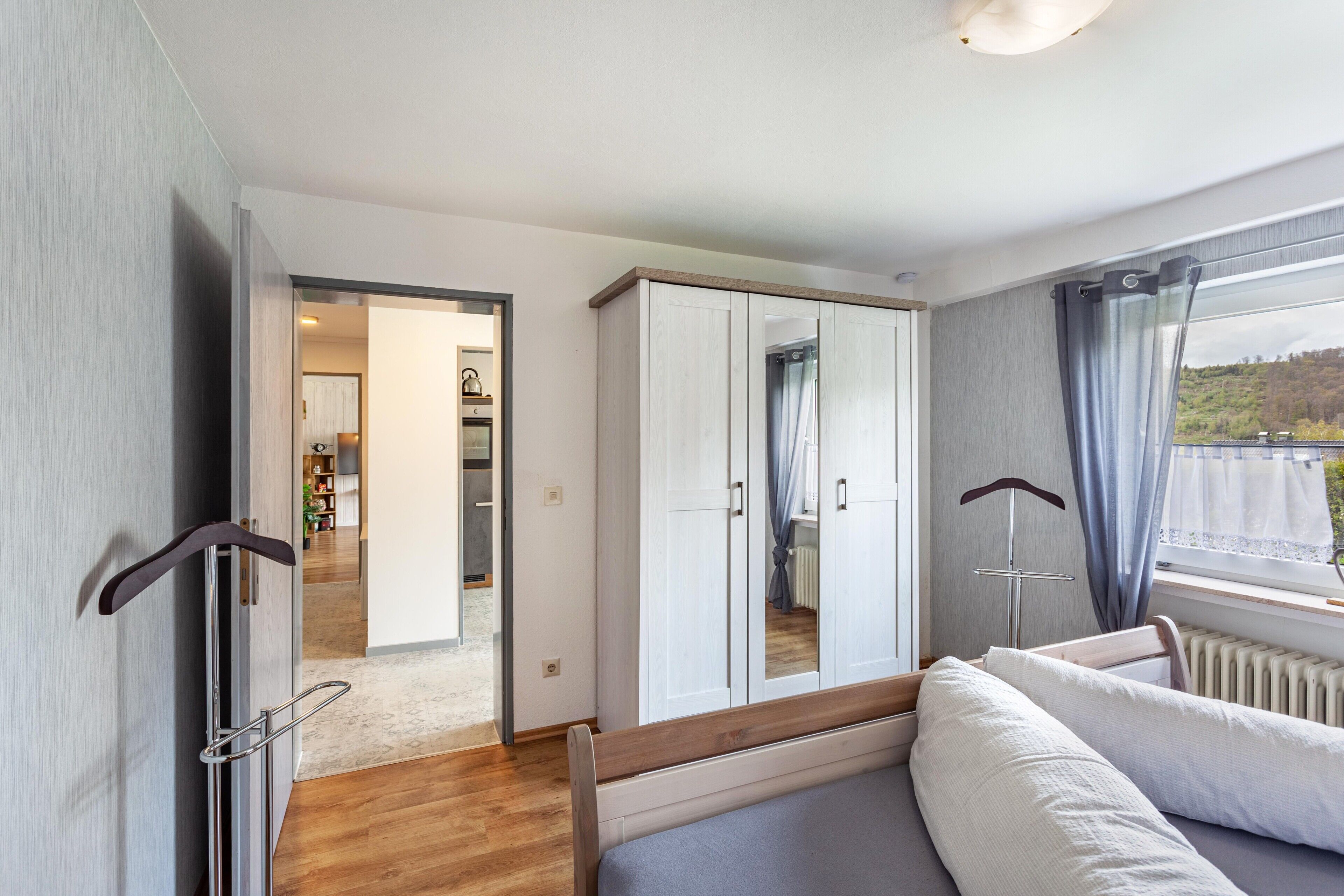 A bedroom with a bed, wardrobe, and a view of a balcony.