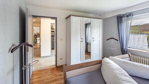 Un dormitorio con cama, armario y vistas a un balcón.