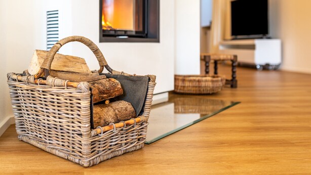 A wicker basket with logs on a wooden floor, a fireplace, and a television in a living room. - Holiday Apartment "Merkurblick" with Mountain View & Private Terrace, WLAN (Baden-Baden)