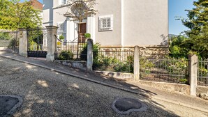 A two-story building with a stone entrance, a gated driveway, and a well-maintained garden. - Holiday Apartment "Merkurblick" with Mountain View & Private Terrace, WLAN (Baden-Baden)