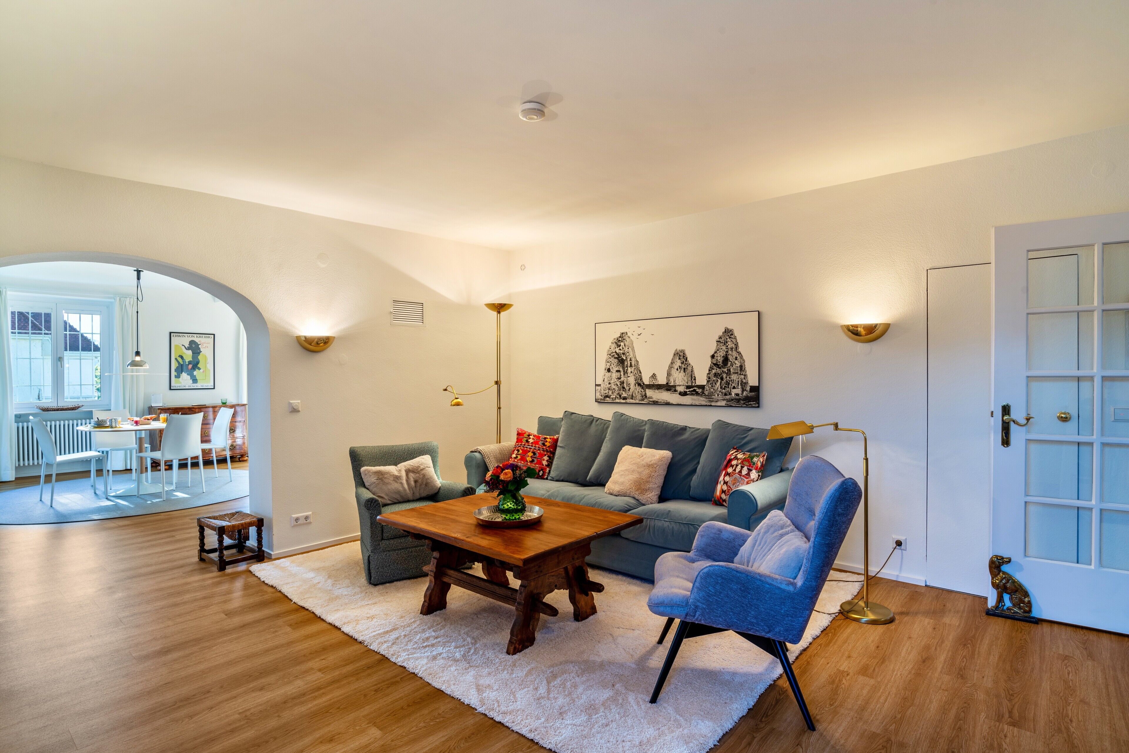 Ein Wohnzimmer mit Sofa, Sesseln, Couchtisch und einem Bild an der Wand.
