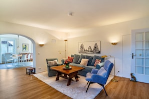 A living room with a sofa, armchair, coffee table, and a painting on the wall.