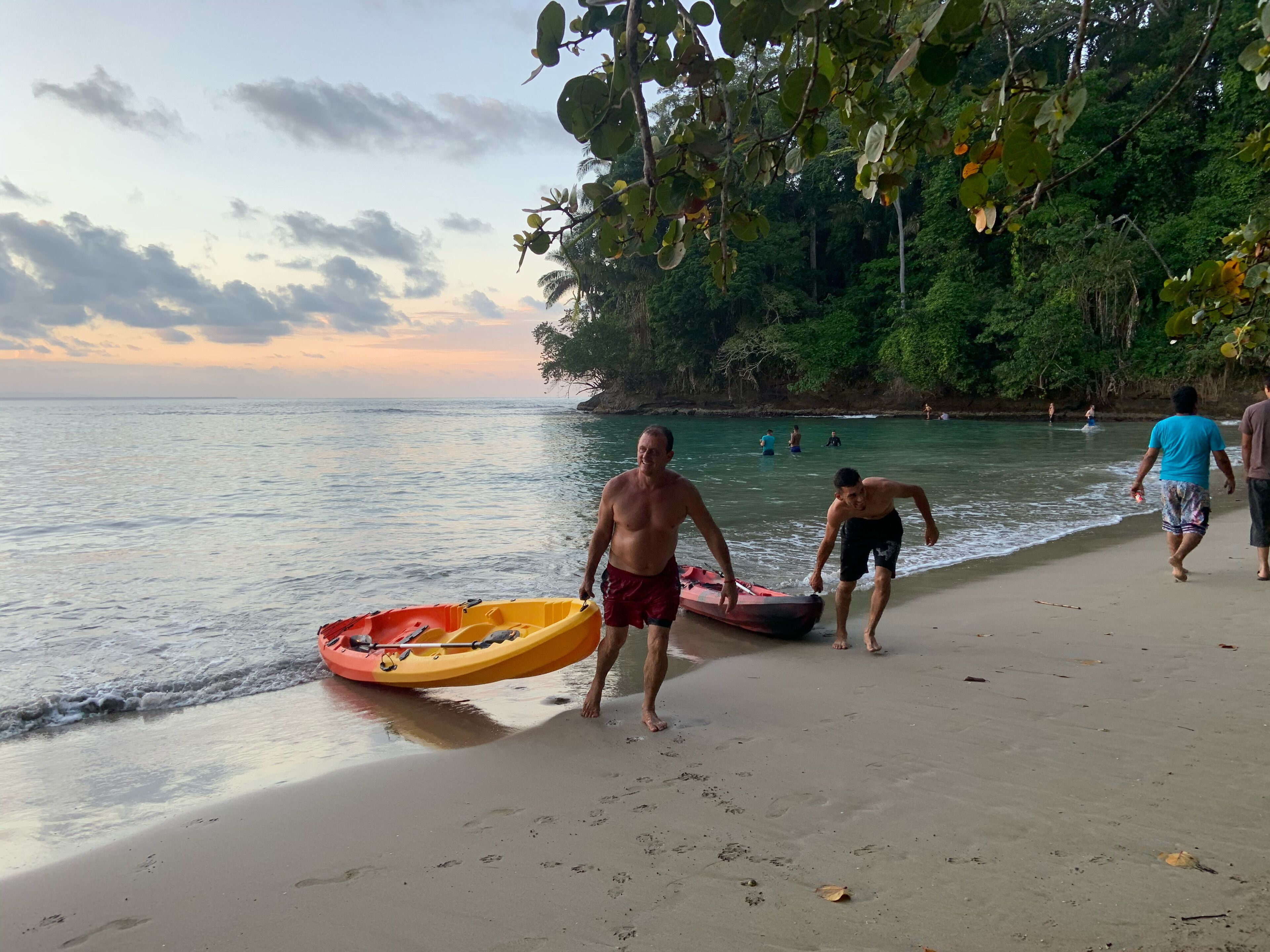 Une scène de plage avec des personnes qui se promènent et un kayak sur le sable.